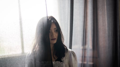 A person dressed as a ghost behind transparent fabric.